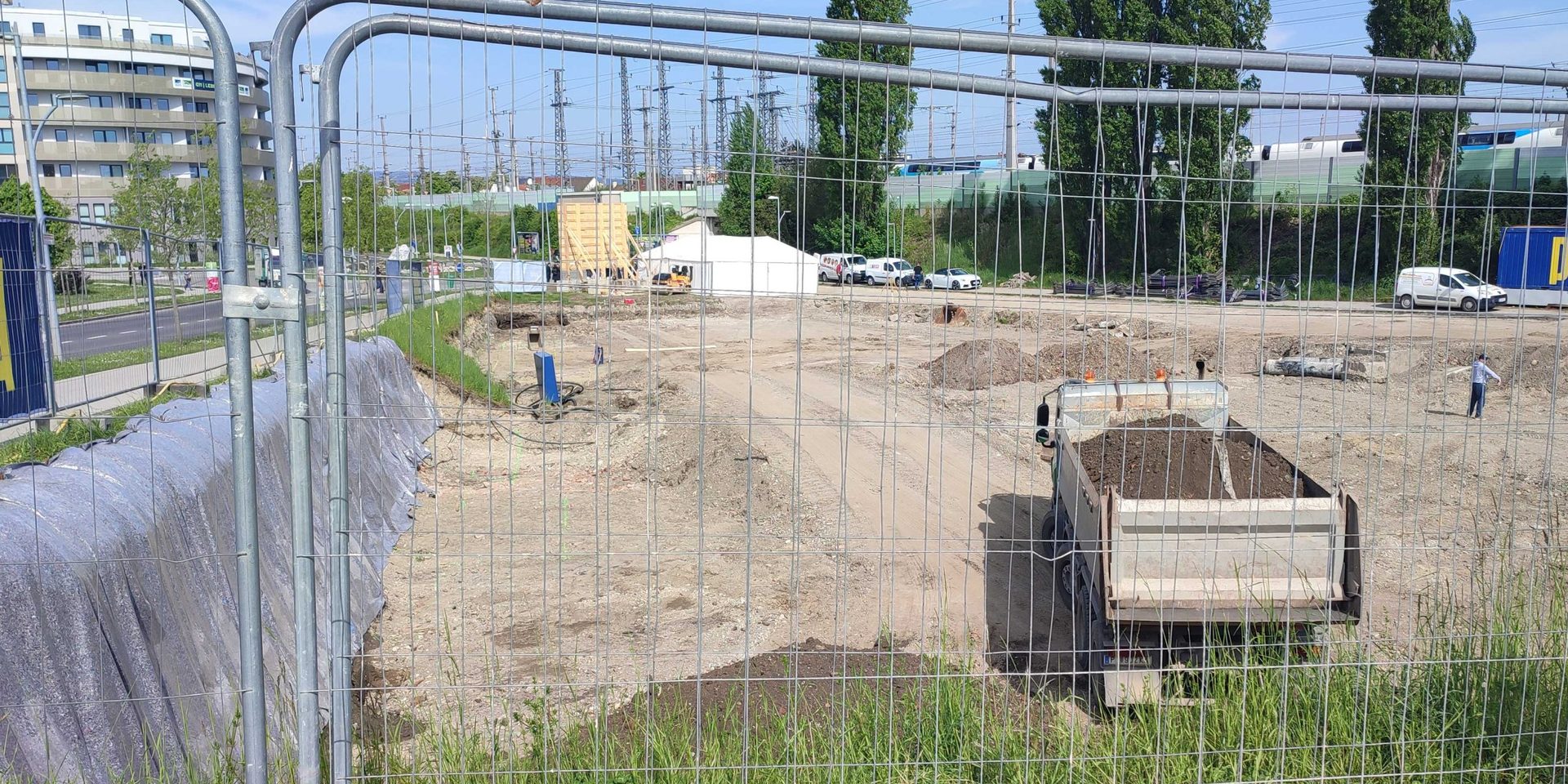 Baustelle der Parkgarage mit Lastwagen hinter Bauzaun
