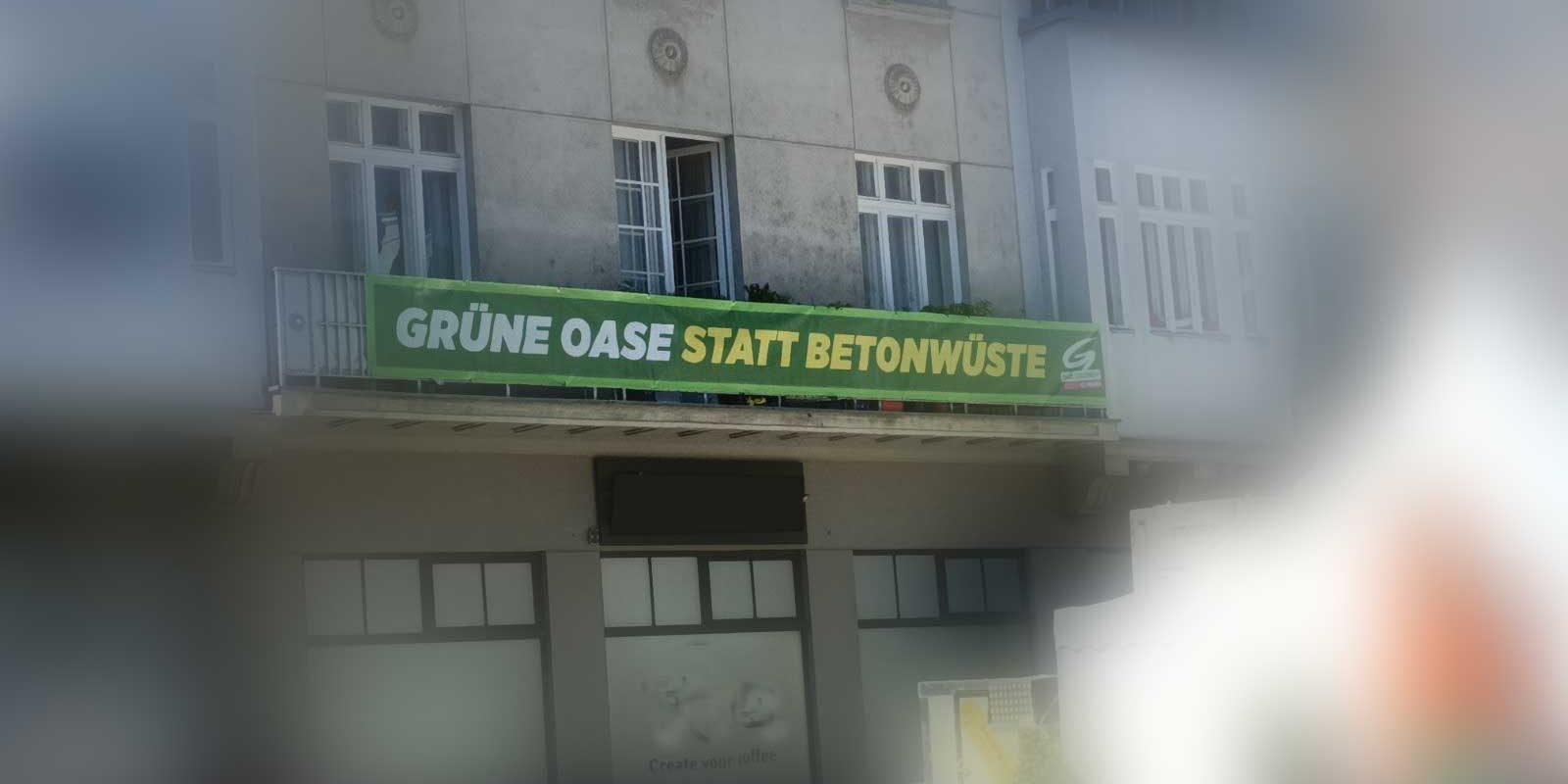 Transparent mit Aufschrift 'Grüne Oase statt Betonwüste' auf Balkongeländer an einem Haus am Domplatz St. Pölten