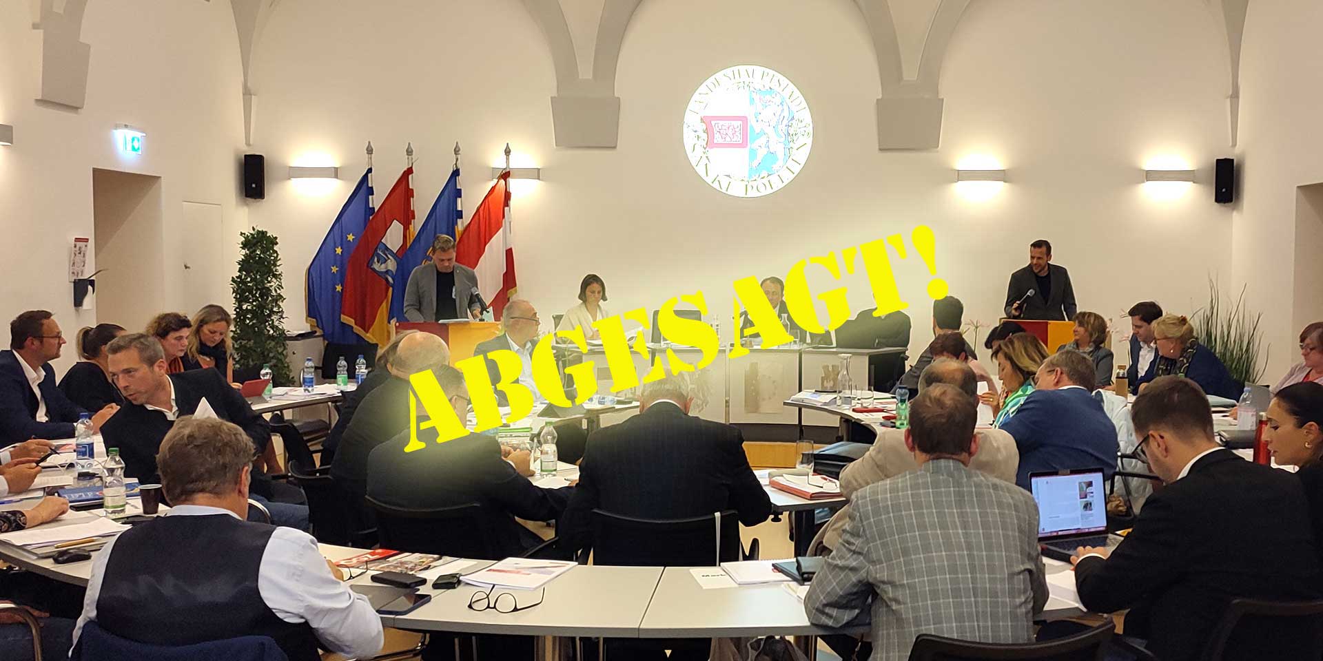 Schriftzug 'Abgesagt' über Bild von gemeinderatssitzung