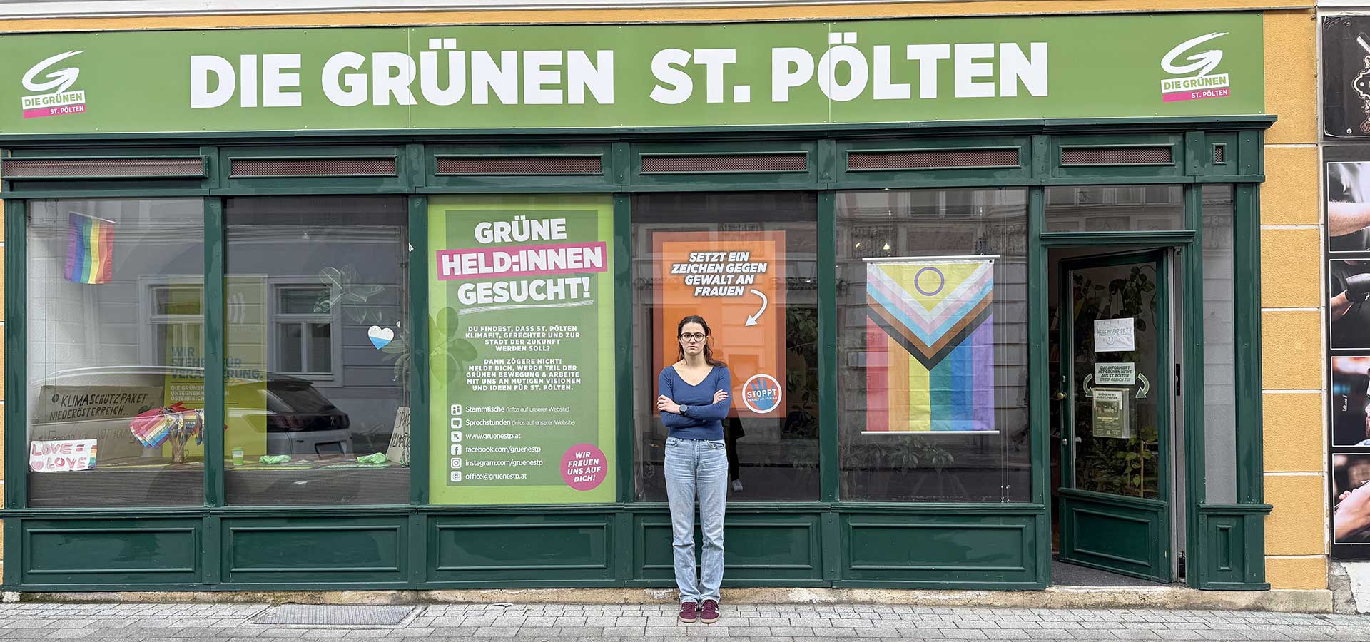 Junge Frau vor einem Plakat in der Auslage des Grünen Büros