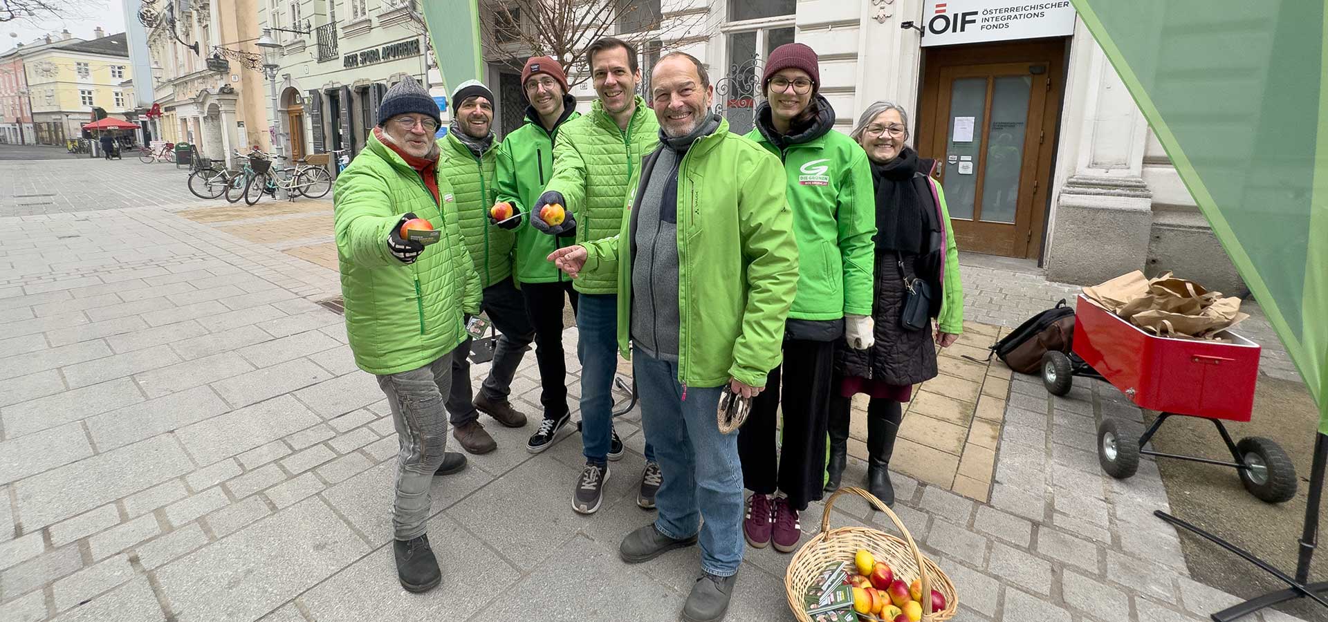 Menschen in grünen Parteijacken bieten Äpfel und Infomaterial in der St. Pöltner Innenstadt an