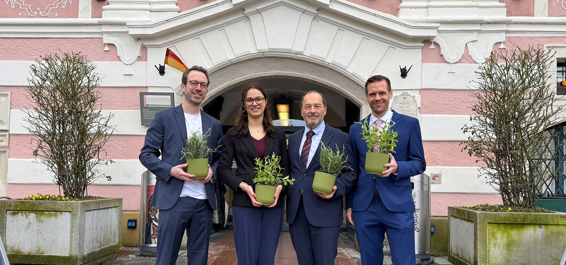 Vier festlich gekleidete Personen mit Blumentöpfen vor dem Eingang des St. Pöltner Rathauses