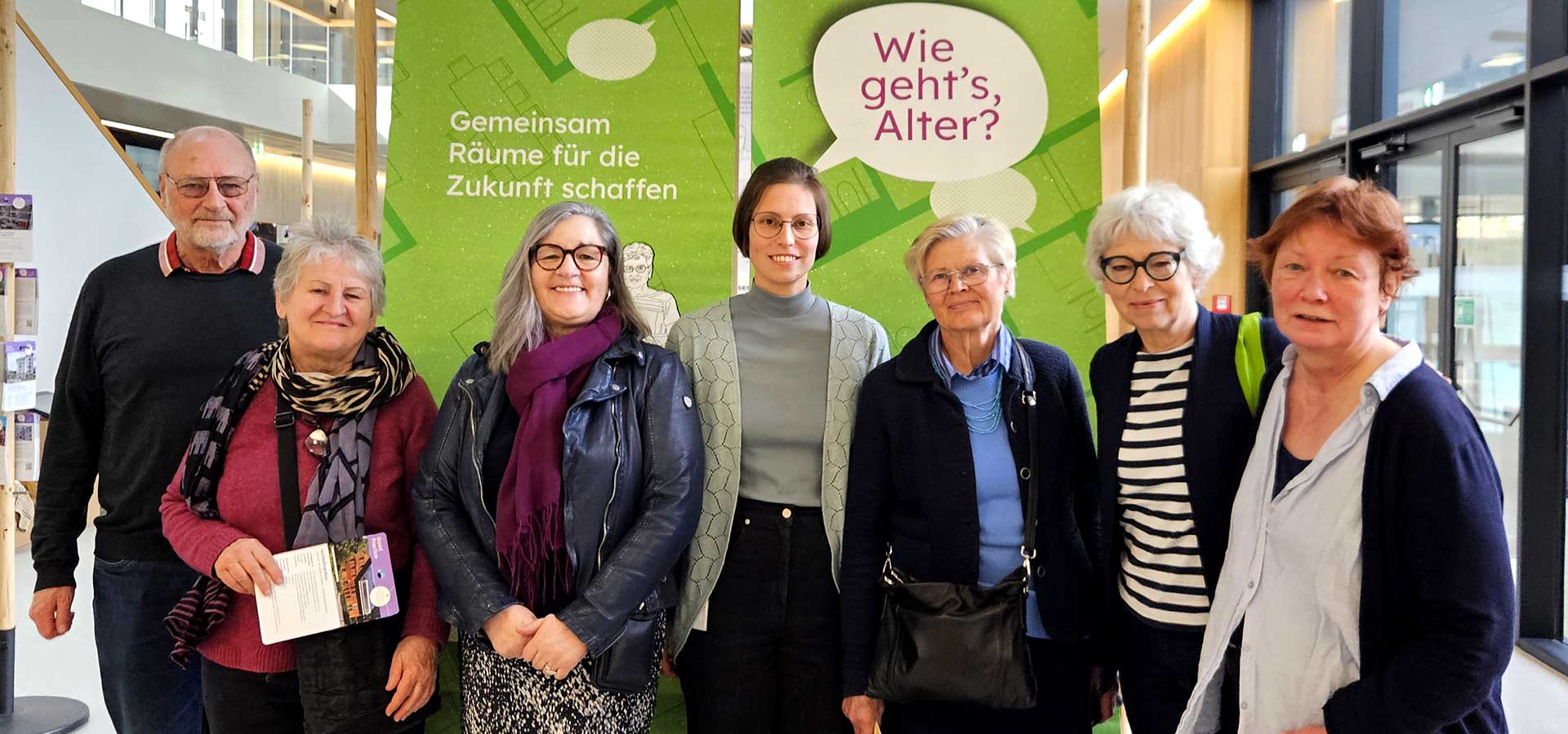 Ältere Menschen (Mitglieder der Grünen Generation plus St. Pölten ) vor einer Plakatwand zum Thema Älter werden